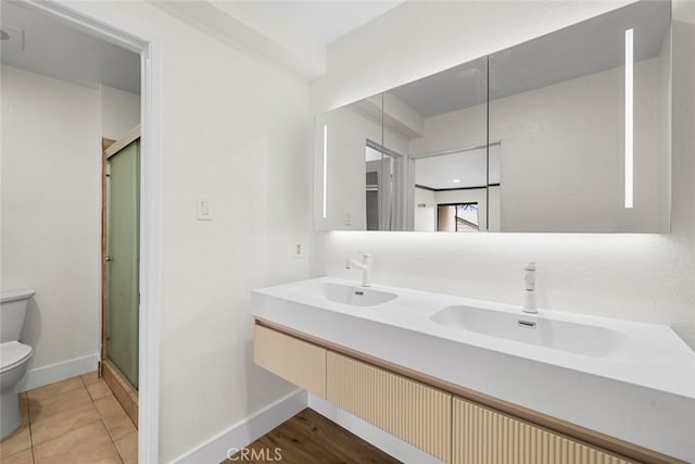 bathroom with tile patterned flooring, vanity, an enclosed shower, and toilet