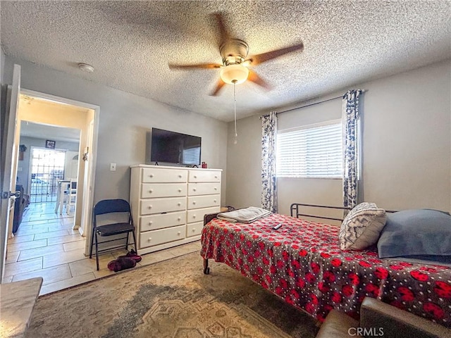 bedroom with multiple windows, ceiling fan, tile patterned flooring, and a textured ceiling