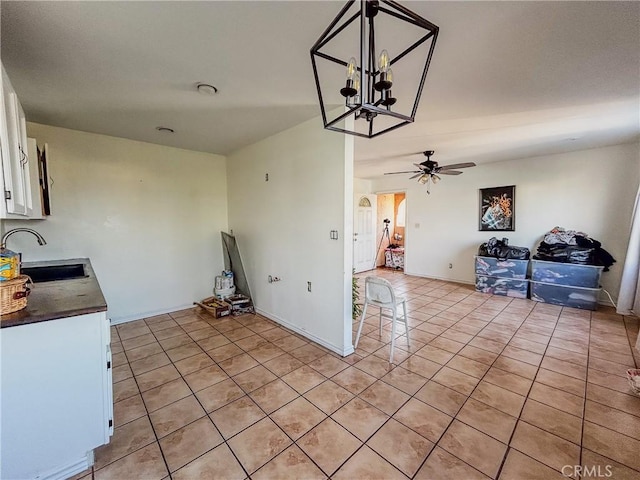 kitchen featuring light tile patterned flooring, sink, ceiling fan with notable chandelier, and white cabinets