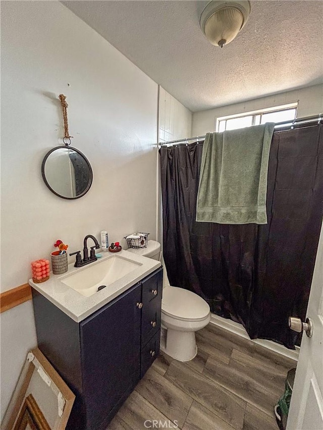 bathroom featuring wood-type flooring, toilet, a textured ceiling, and vanity