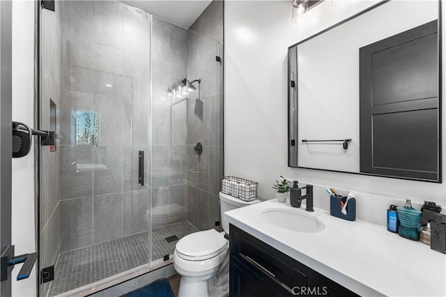 bathroom featuring a shower with door, vanity, and toilet