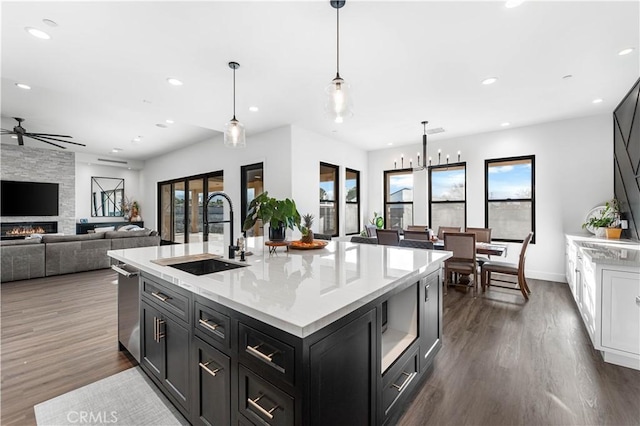 kitchen featuring a center island with sink, sink, pendant lighting, and dark wood-type flooring