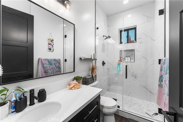 bathroom with toilet, vanity, and a shower with shower door