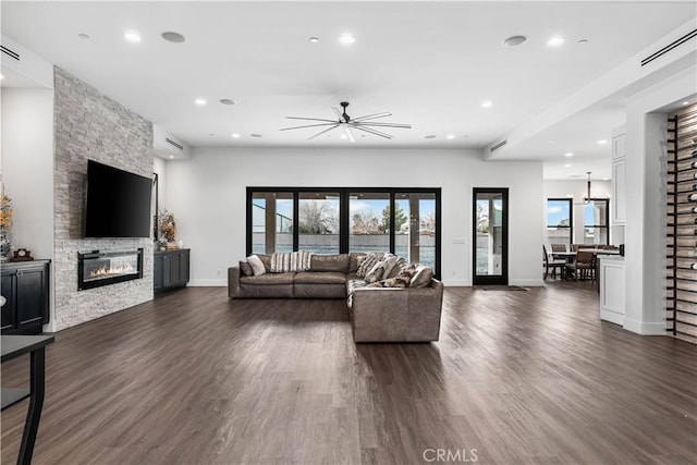 living room featuring a stone fireplace and dark hardwood / wood-style floors