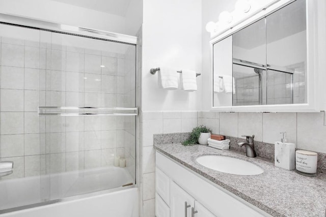 bathroom with tile walls, vanity, and enclosed tub / shower combo