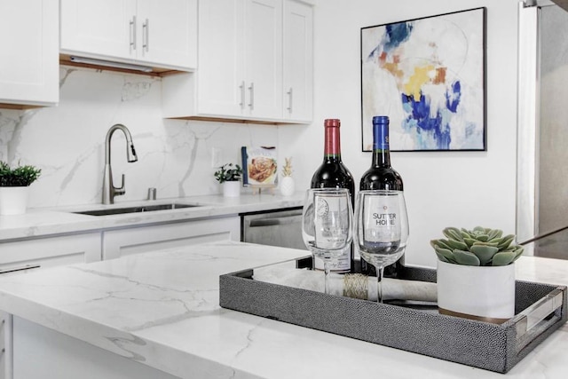 kitchen featuring tasteful backsplash, dishwasher, sink, and white cabinets