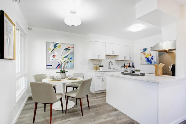 kitchen featuring tasteful backsplash, white cabinetry, sink, and light wood-type flooring