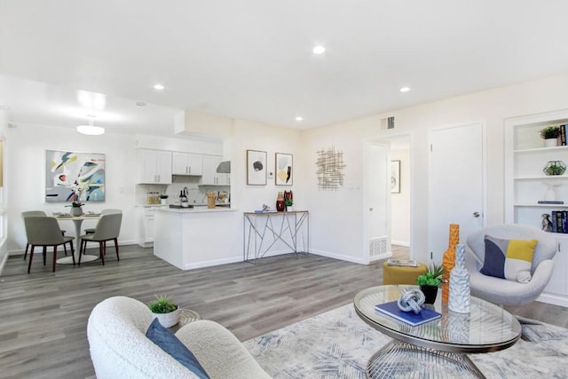 living room with wood-type flooring and built in shelves