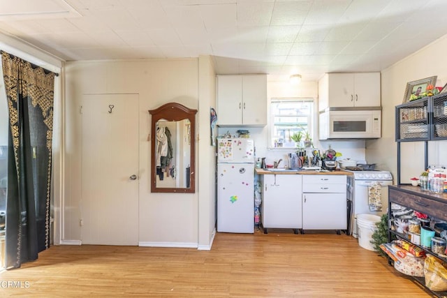 kitchen with white cabinetry, light wood-type flooring, and white appliances