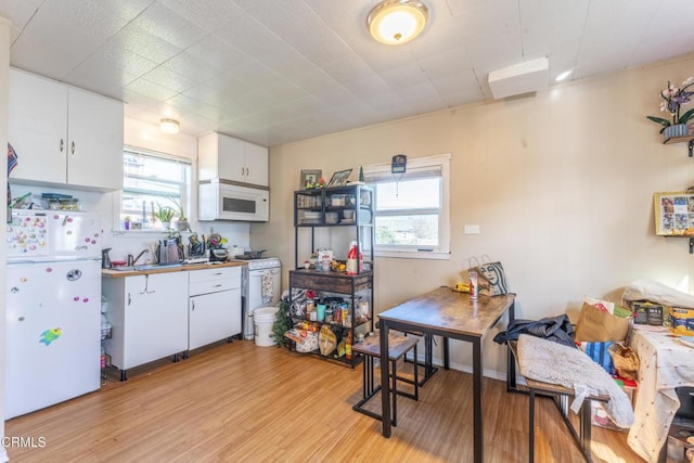 kitchen featuring white cabinetry, white appliances, light hardwood / wood-style floors, and a healthy amount of sunlight