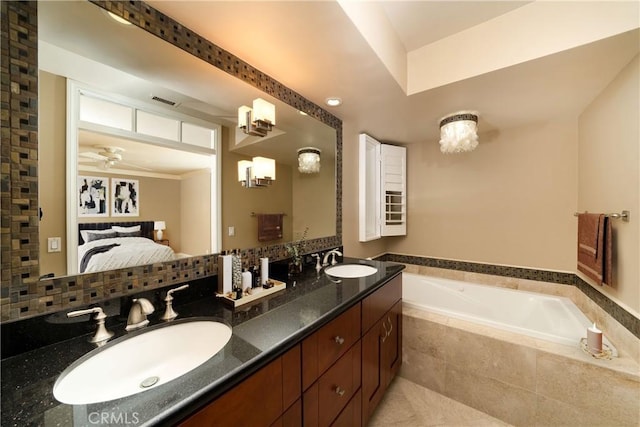 bathroom with ceiling fan, vanity, decorative backsplash, and tiled tub