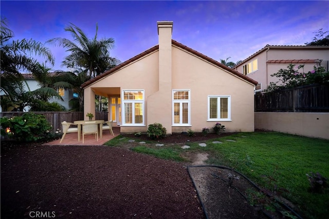12999 Caminito Pointe Del Mar, Del Mar, CA 92014 - back of house at dusk featuring a fenced backyard, a patio area, stucco siding, and a chimney