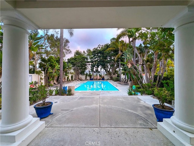 pool at dusk featuring a patio