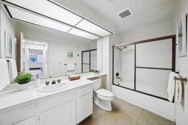 full bathroom featuring enclosed tub / shower combo, vanity, and toilet