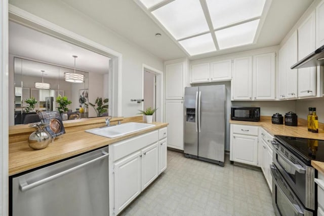 kitchen featuring pendant lighting, appliances with stainless steel finishes, sink, and white cabinets