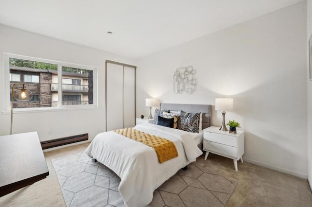 bedroom with light carpet, a baseboard heating unit, and a closet