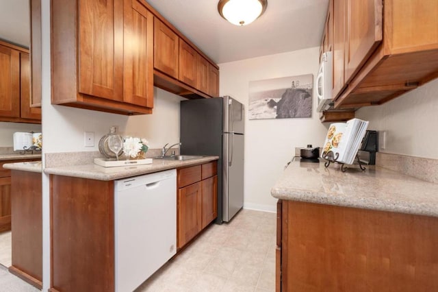 kitchen featuring white appliances, light stone countertops, and sink