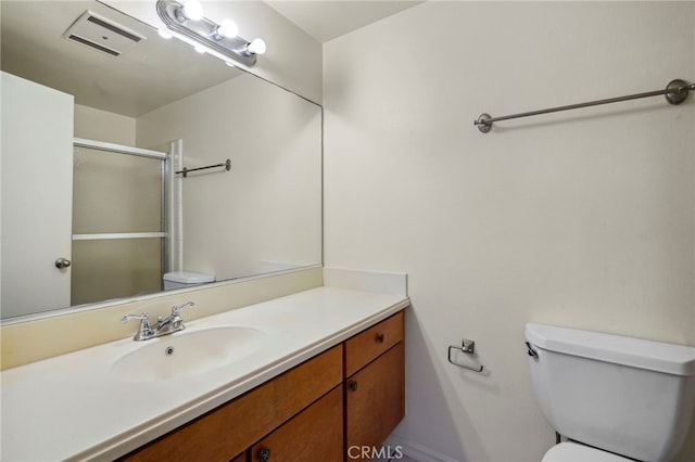 bathroom with vanity, a shower with shower door, and toilet