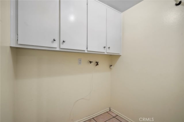 clothes washing area with cabinets and light tile patterned floors