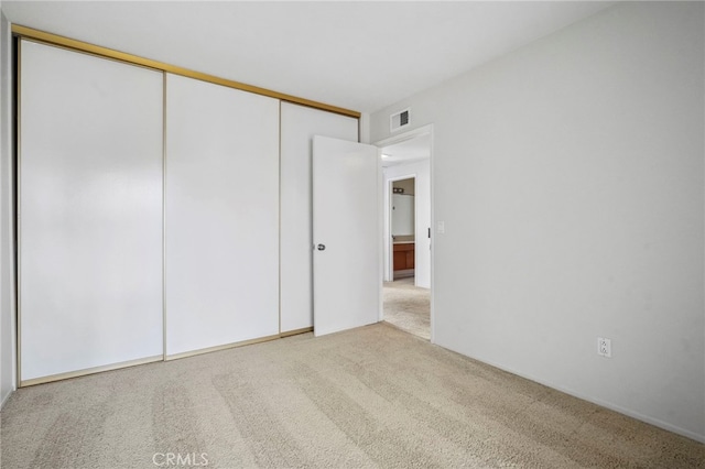 unfurnished bedroom with light colored carpet and a closet