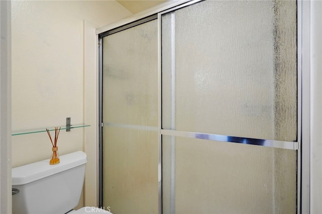 bathroom with a shower with shower door and toilet