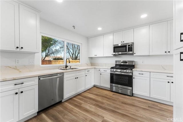 kitchen featuring white cabinetry, appliances with stainless steel finishes, sink, and hardwood / wood-style flooring