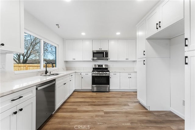 kitchen featuring light wood-type flooring, appliances with stainless steel finishes, sink, and white cabinets