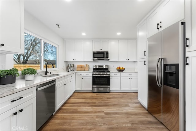 kitchen with white cabinetry, stainless steel appliances, light hardwood / wood-style floors, and sink