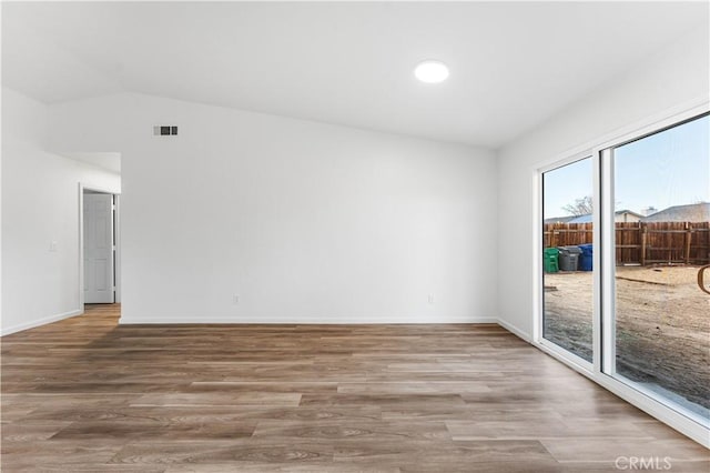 unfurnished room featuring vaulted ceiling and hardwood / wood-style floors