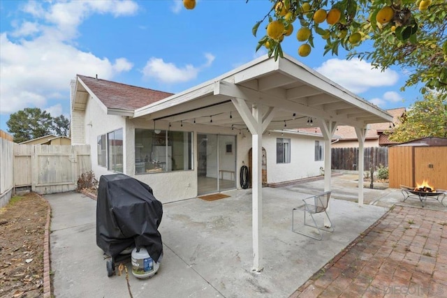 back of property with a fire pit and a patio