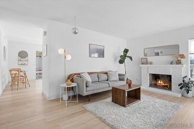 living room with a brick fireplace and light wood-type flooring