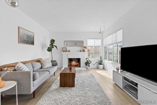 living room with a fireplace, light hardwood / wood-style floors, and an AC wall unit