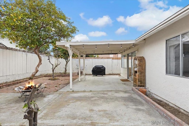 view of patio with area for grilling and a fire pit