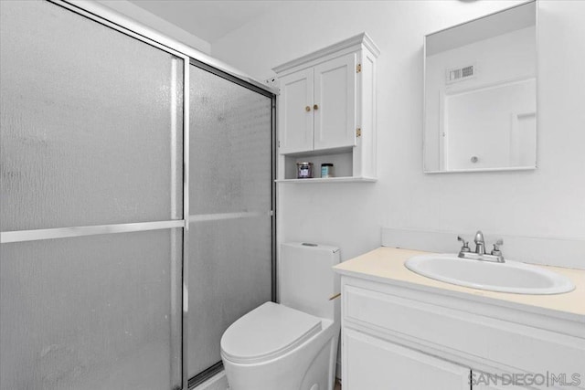 bathroom featuring vanity, toilet, and a shower with door