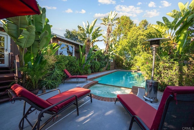 pool with a patio and an in ground hot tub