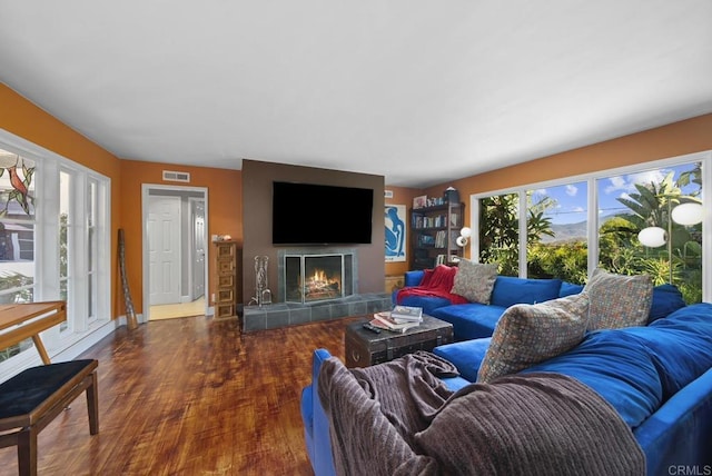 living room with baseboards, a fireplace, visible vents, and dark wood-type flooring