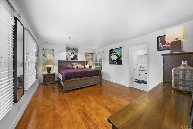 bedroom featuring recessed lighting, ensuite bath, baseboards, and wood finished floors