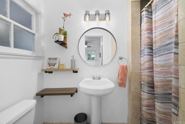 bathroom with toilet, a shower with curtain, and ceiling fan