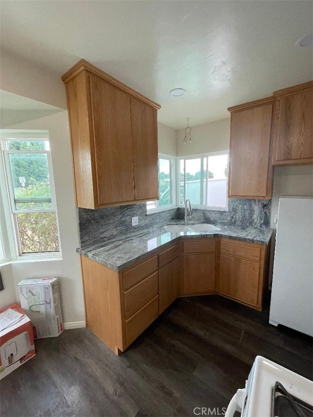 kitchen featuring tasteful backsplash, sink, dark wood-type flooring, and light stone counters