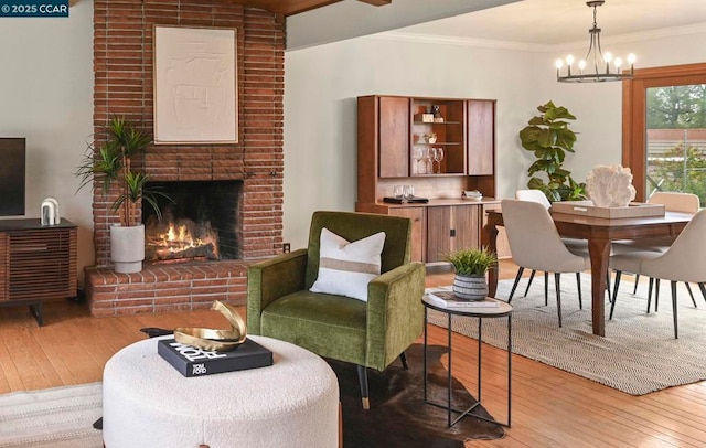 interior space featuring ornamental molding, an inviting chandelier, a fireplace, and light hardwood / wood-style floors