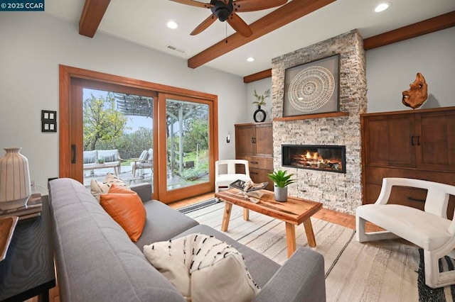 living room with ceiling fan, a fireplace, light hardwood / wood-style floors, and beamed ceiling