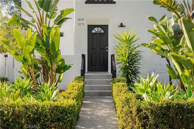 property entrance featuring fence and stucco siding