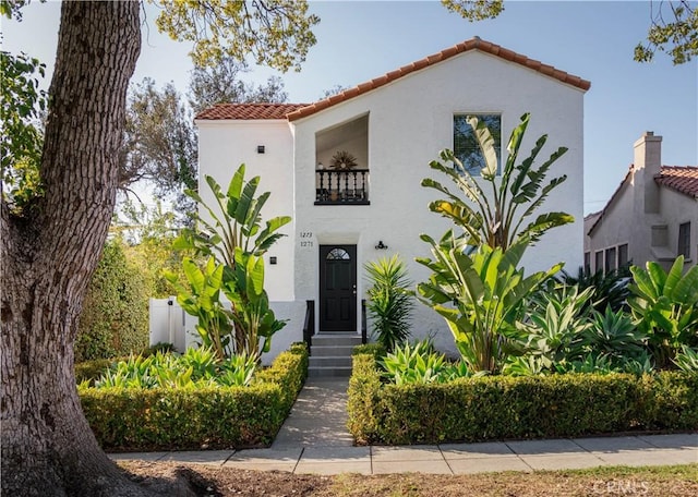 mediterranean / spanish house featuring entry steps, a tiled roof, a balcony, and stucco siding