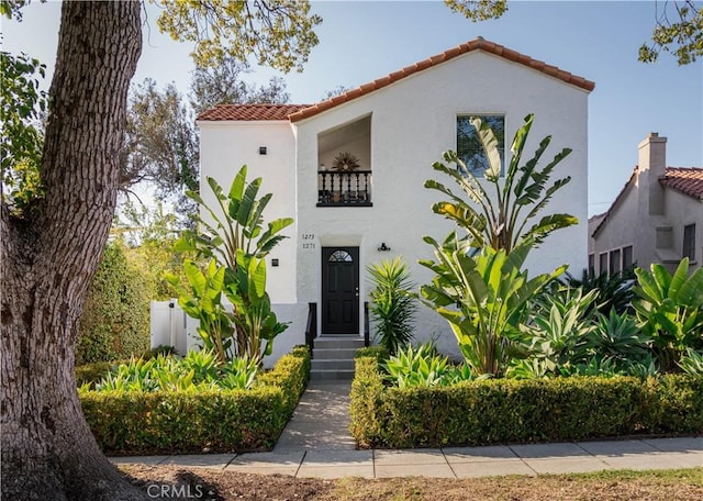 mediterranean / spanish-style home with stucco siding, a balcony, entry steps, and a tiled roof