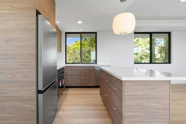 kitchen featuring appliances with stainless steel finishes, pendant lighting, and light wood-type flooring