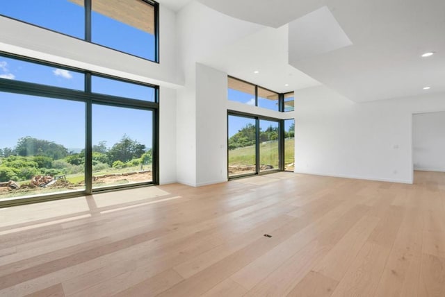 unfurnished living room with a high ceiling and light wood-type flooring