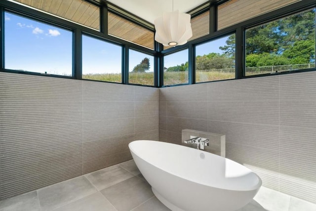 bathroom with a bath, tile patterned floors, and tile walls