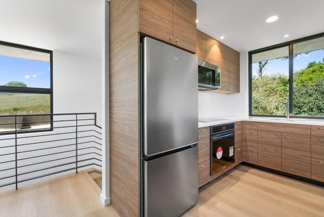 kitchen featuring stainless steel appliances, sink, and light wood-type flooring