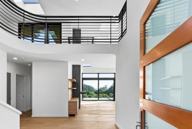 entrance foyer featuring a towering ceiling, a skylight, and light wood-type flooring