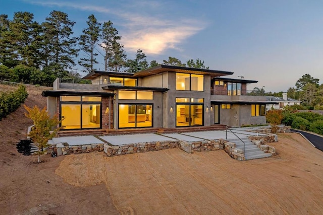 back house at dusk with a patio and a balcony